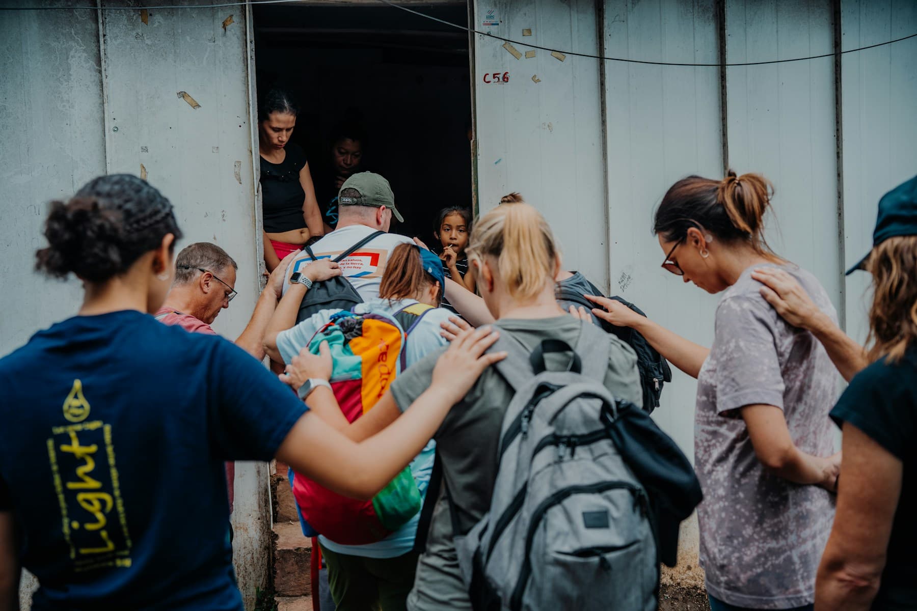 Voluntários reunidos em círculo à entrada de um edifício